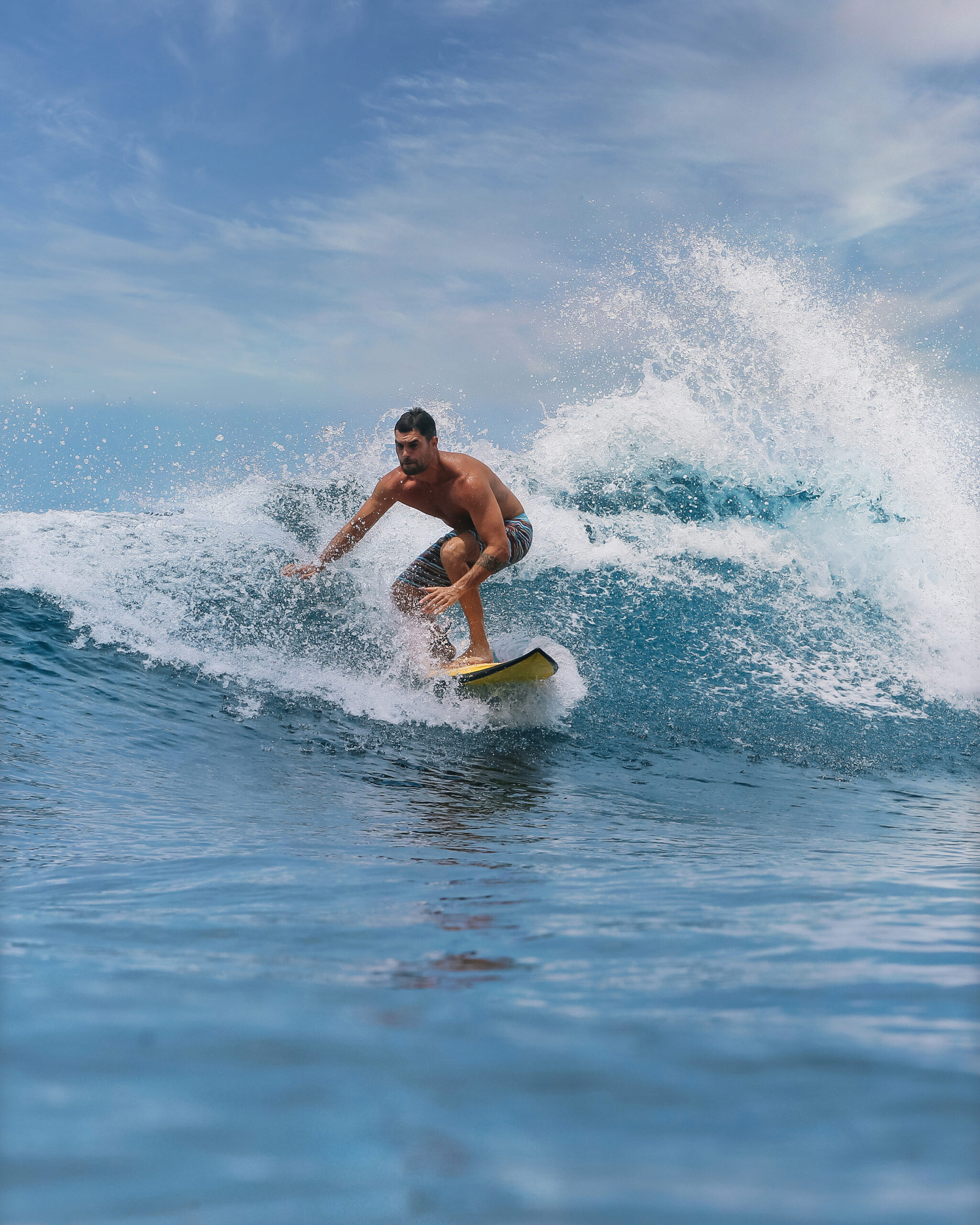 Male surfer on a blue wave at Bali island